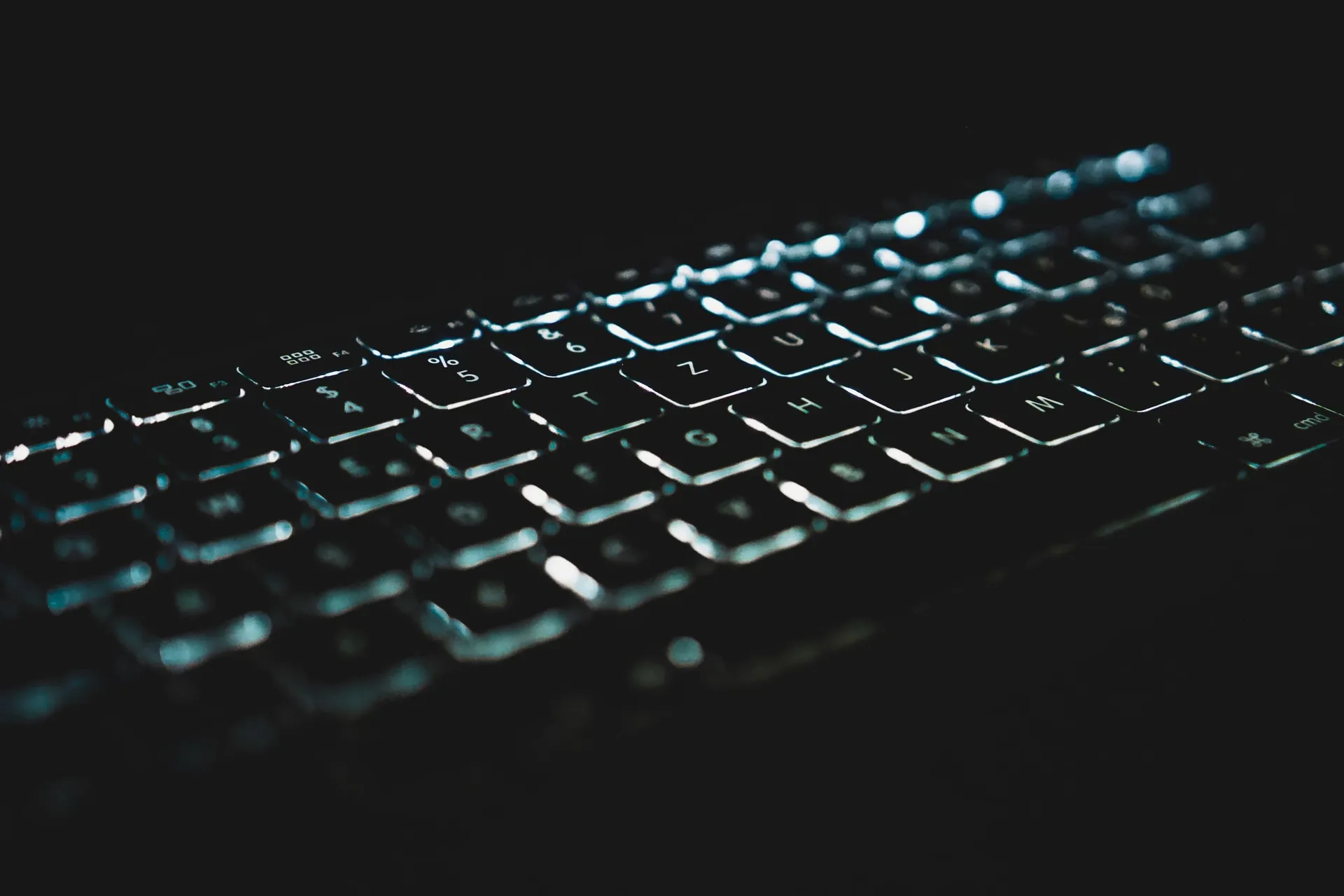 Keyboard lit in teal in a dark room