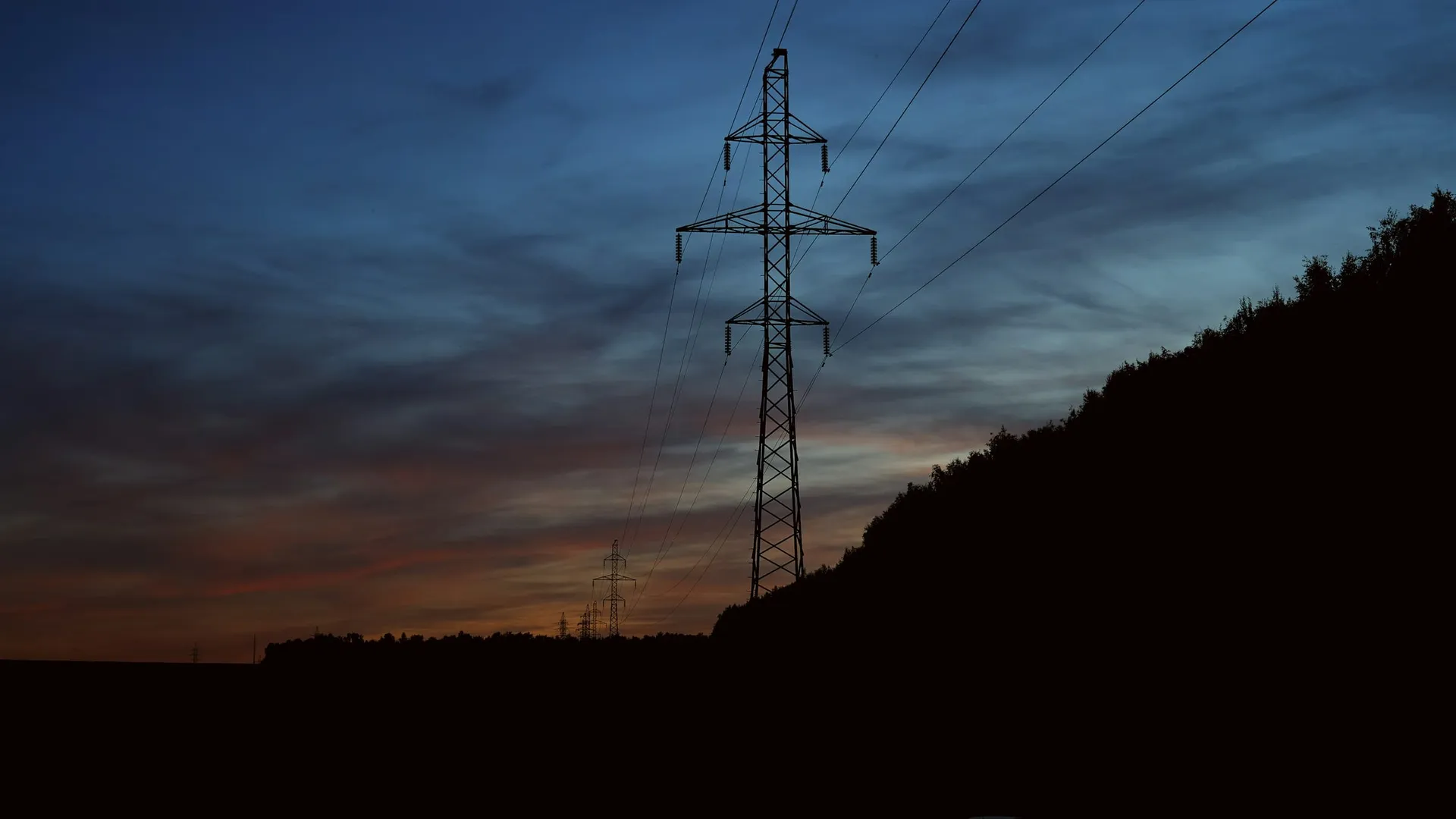 Electricity pylon silhouetted against the evening sky
