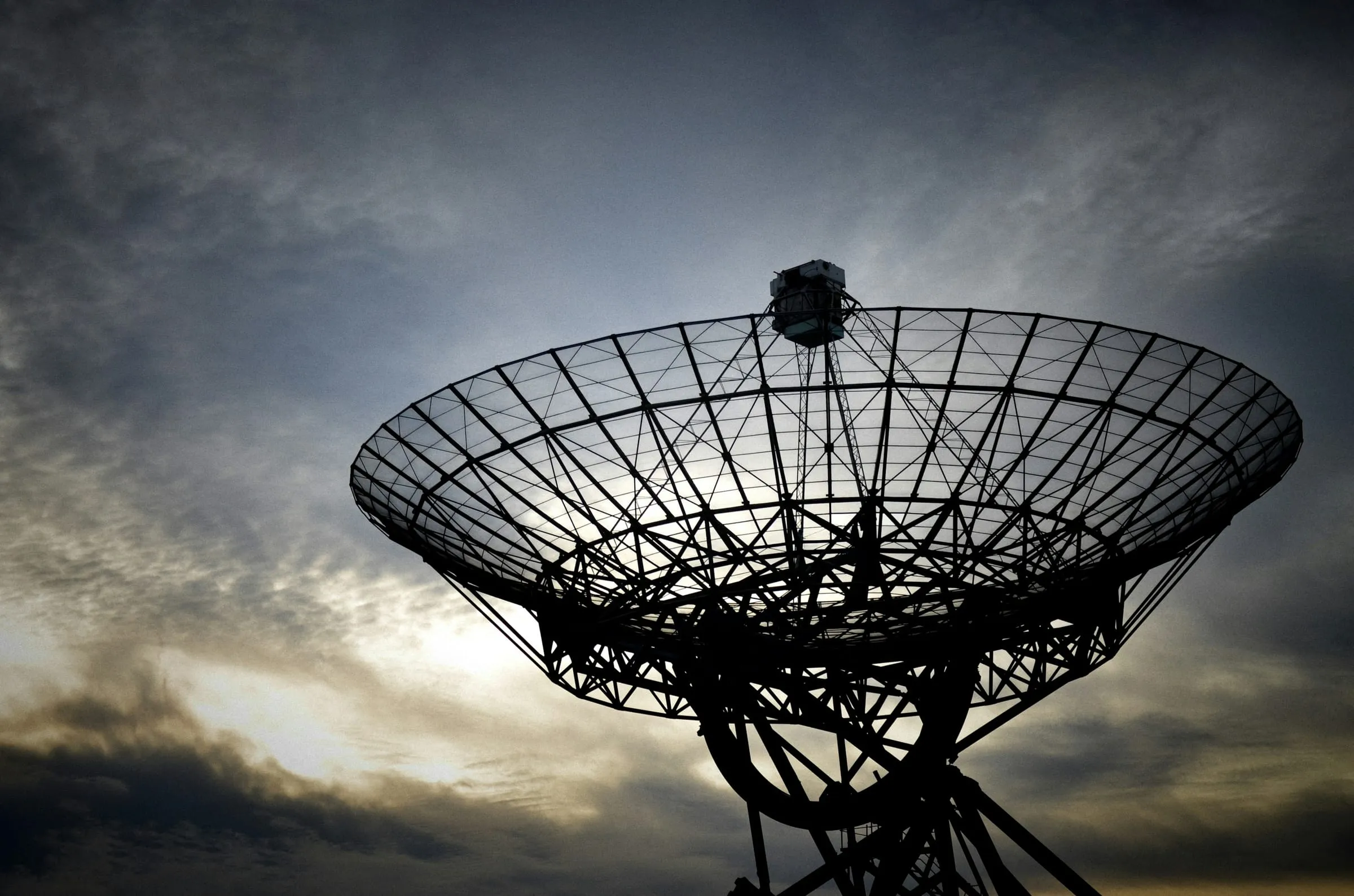 Open-mesh parabolic antenna against a cloudy sky