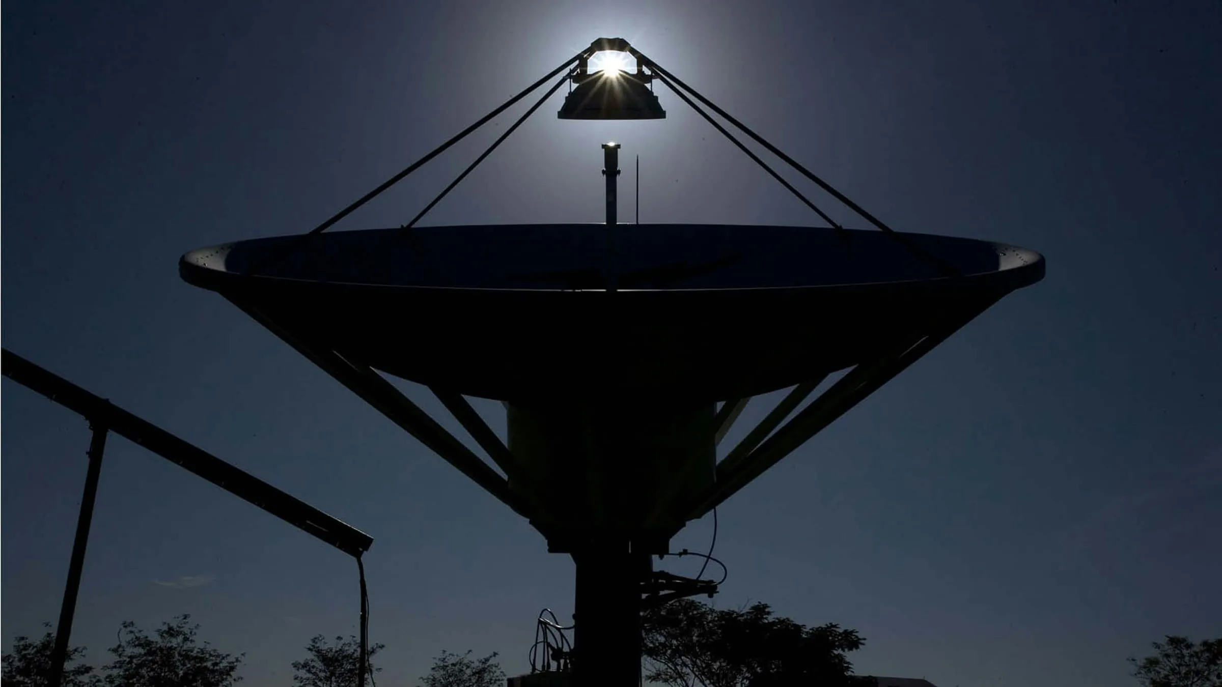 Satellite dish silhouetted against the night sky